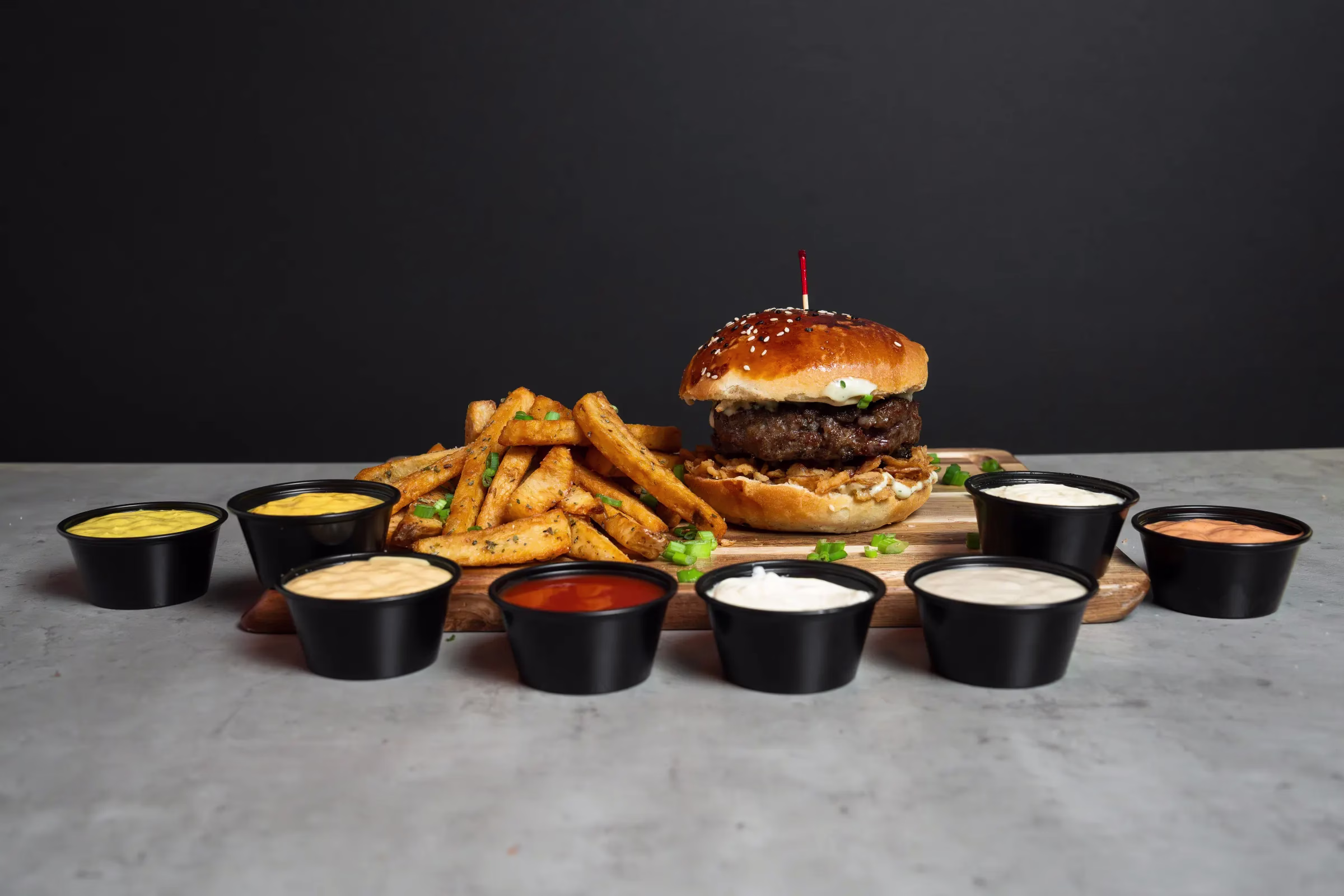 FRIES B4 GUYS burger and Dutch-style fries with all 8 homemade sauces lined up on a wooden board at our Allston, Boston restaurant
