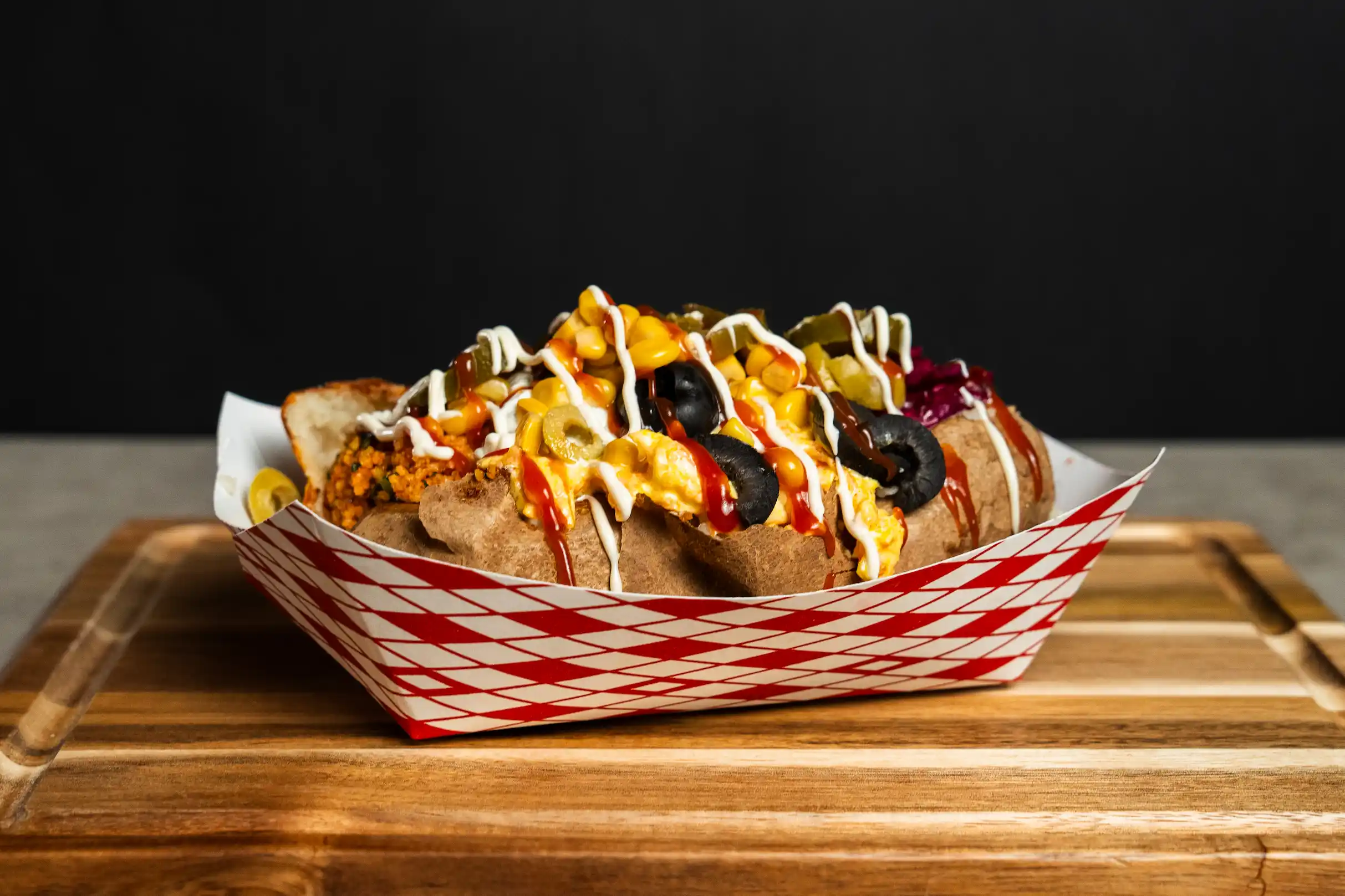 Kumpir loaded with kısır, corn, green and black olives, jalape&ntilde;os, and sauces at Fries B4 Guys in Allston, Boston